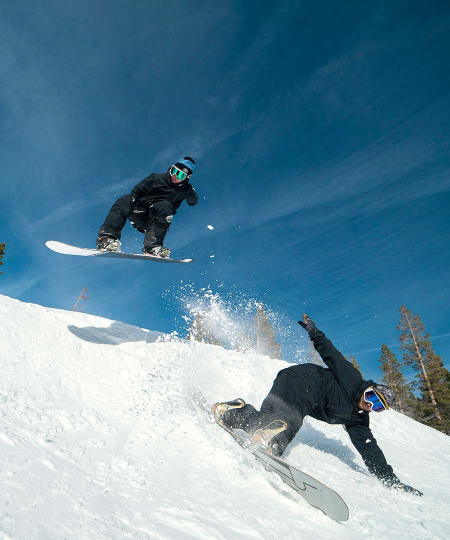 Two employees snowboarding in the terrain park at Sugar Bowl Resort.