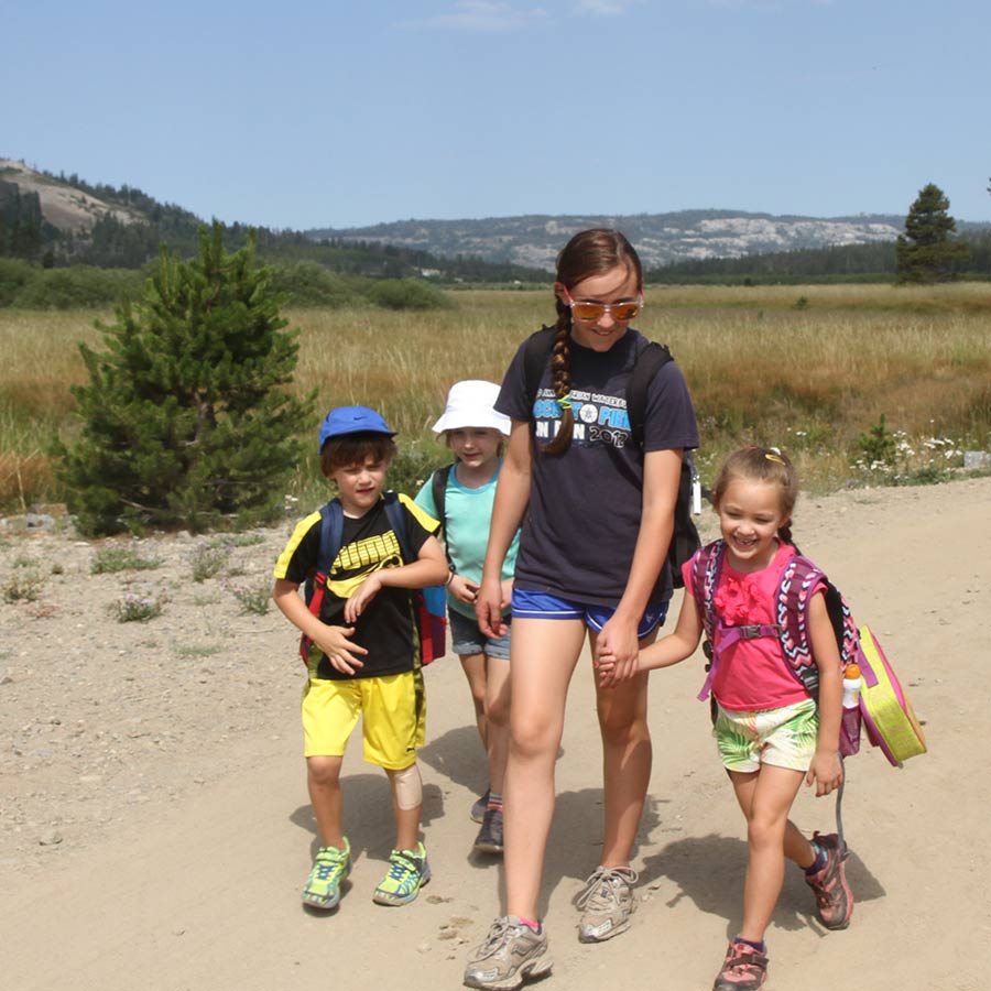 Campers hike through a meadow with a friendly camp councilor at Sugar Bowl Summer Camp