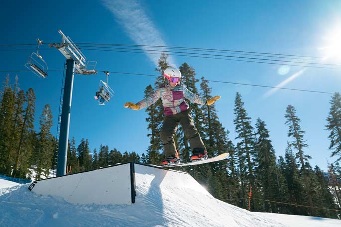 Young Skier having fun learning to hit a box in the terrain park with the mountain shredders