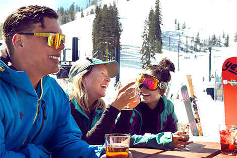 Group of friends enjoying discounted drinks out in the sun on the Village Lodge Deck.