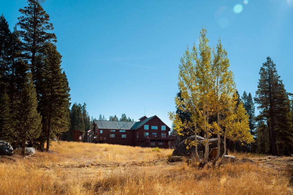 View of Royal Gorge Lodge from an Alpine field with a sunny blue sky