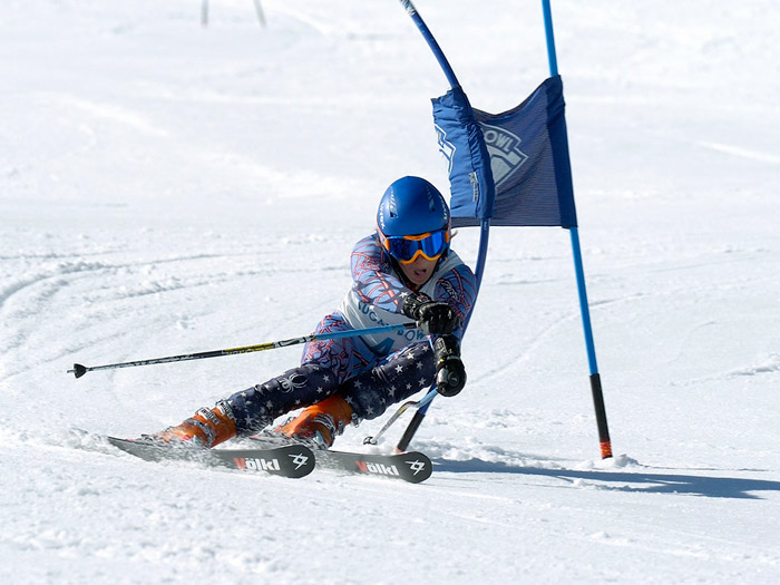 Ski racer making a hard left turn making contact with a Sugar Bowl race gate.