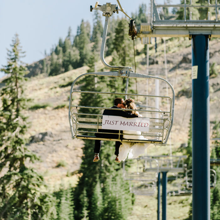 Bride and Groom riding a chairlift up Mt. Disney in the summer with a Just Married sign behind them