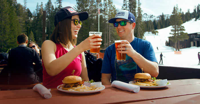 Couple enjoying burgers and beer on the deck of the Village Lodge at Sugar Bowl Ski Resort