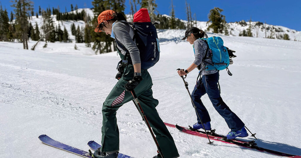 Two skiers travel uphill in the spring.