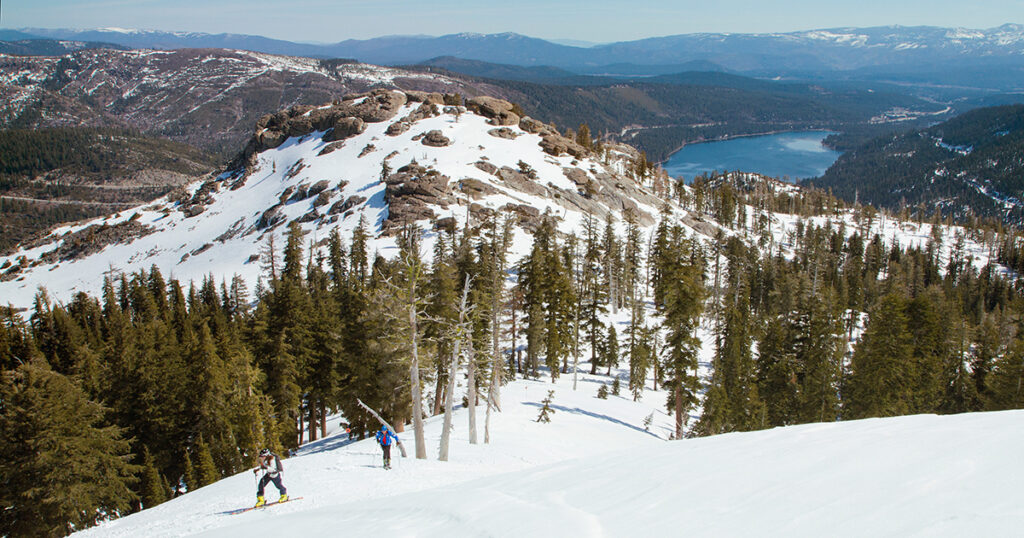 Skier travels uphill with a view of donner lake in the background