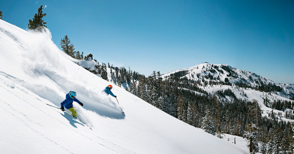 A father and son skiing powder on a bluebird morning.