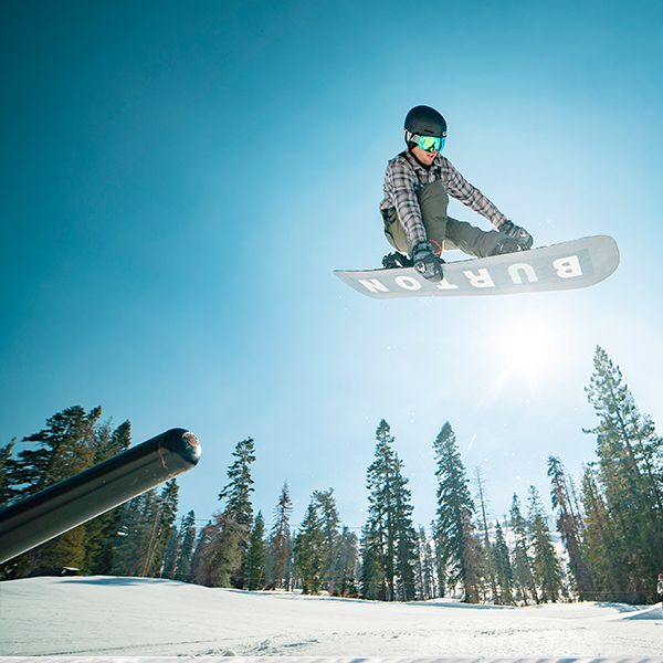 Snowboarder launching off of a rail in the terrain park. 