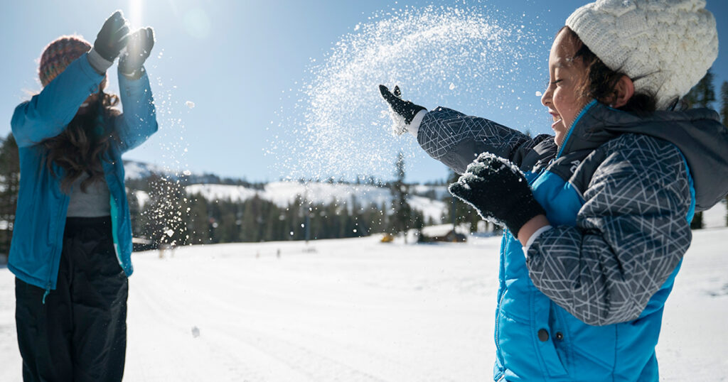 Mother and daughter playing the snow on a sunny day