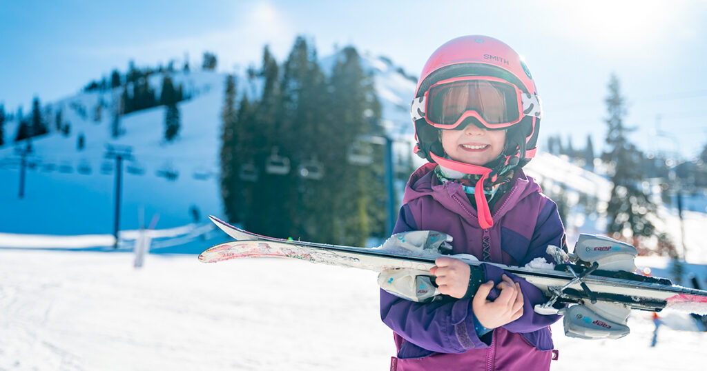 Young Girl Carrying Skis and Smiling