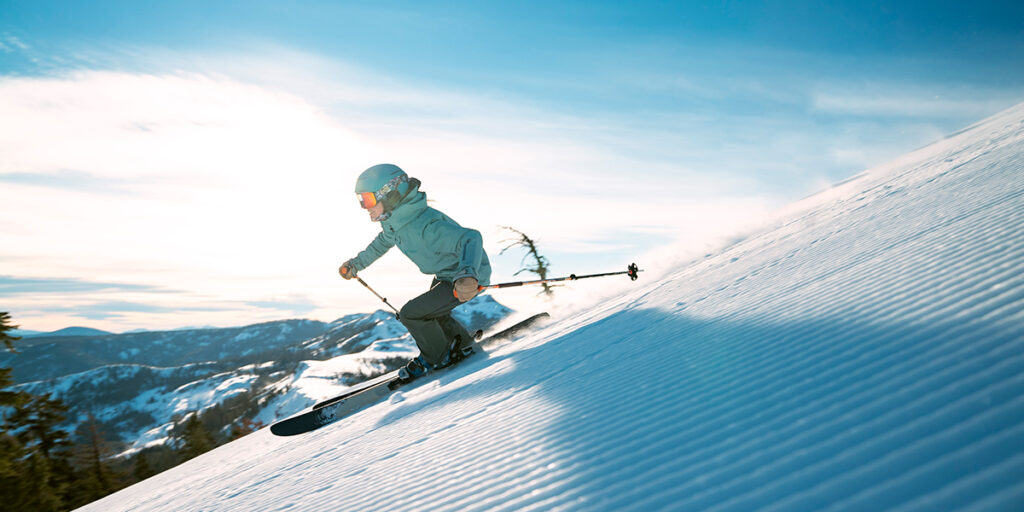 Crisp corduroy on a steep run with a view of the mountain range behind