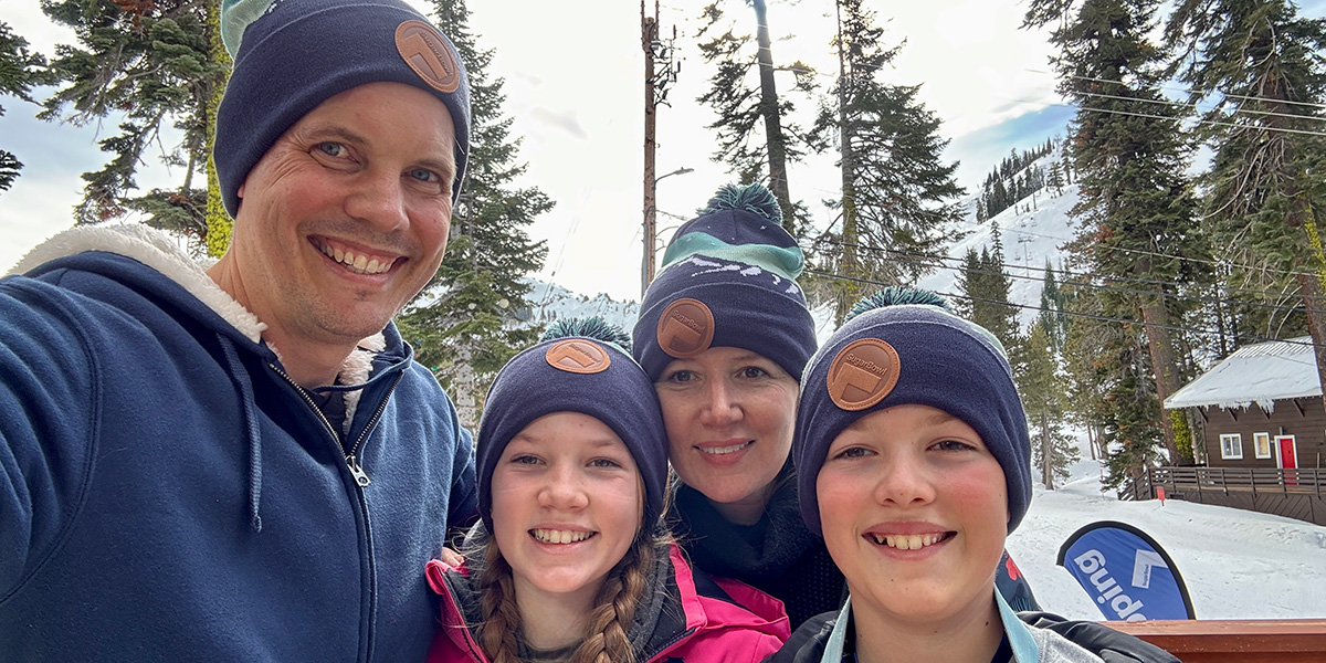 A family posing for a photo wearing passholder beanies at a Sugar Bowl beanie drop.