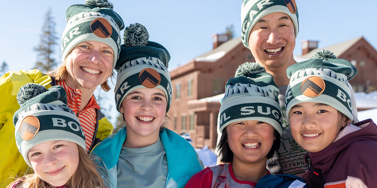 A family posing for a photo wearing passholder beanies at a Sugar Bowl beanie drop.