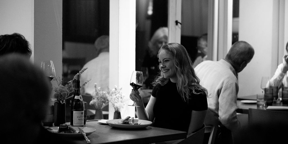 A women sipping a glass of wine and enjoying dinner at the Dining Room in the Village Lodge at Sugar Bowl.