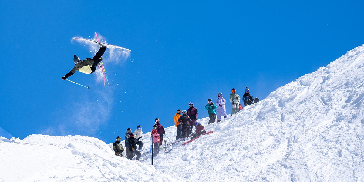 An athlete at the Silver Belt Freeride Competition hits a jump on a sunny powder day.